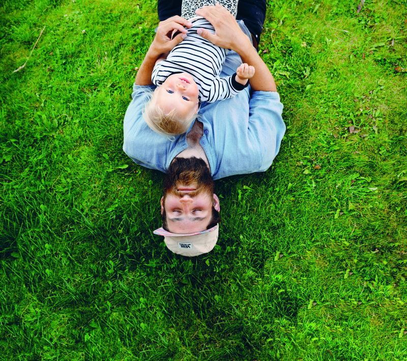 Far og sønn ligger på gress
