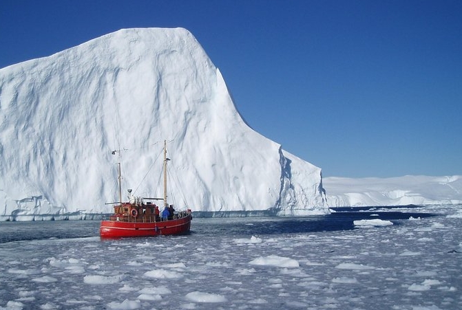 röd båt passerar isberg i Arktis