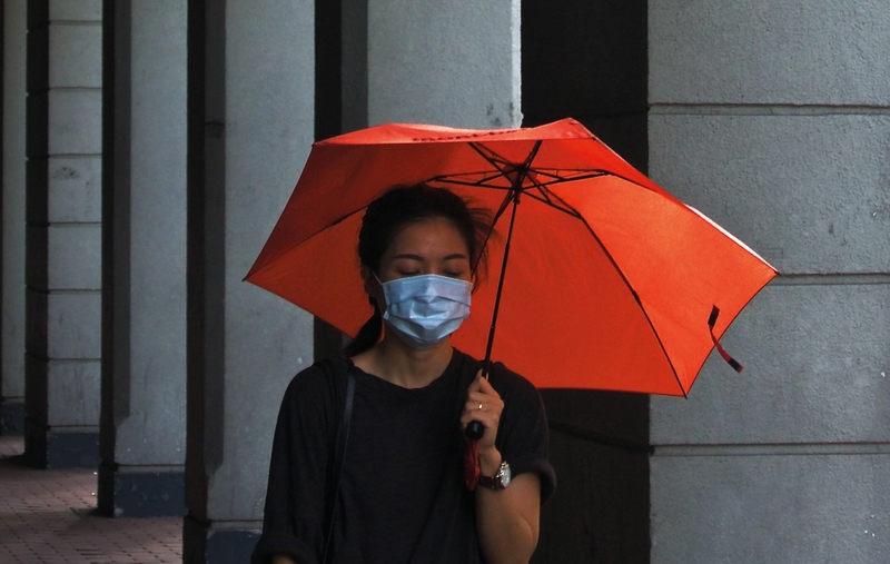kvinna med paraply och munskydd
