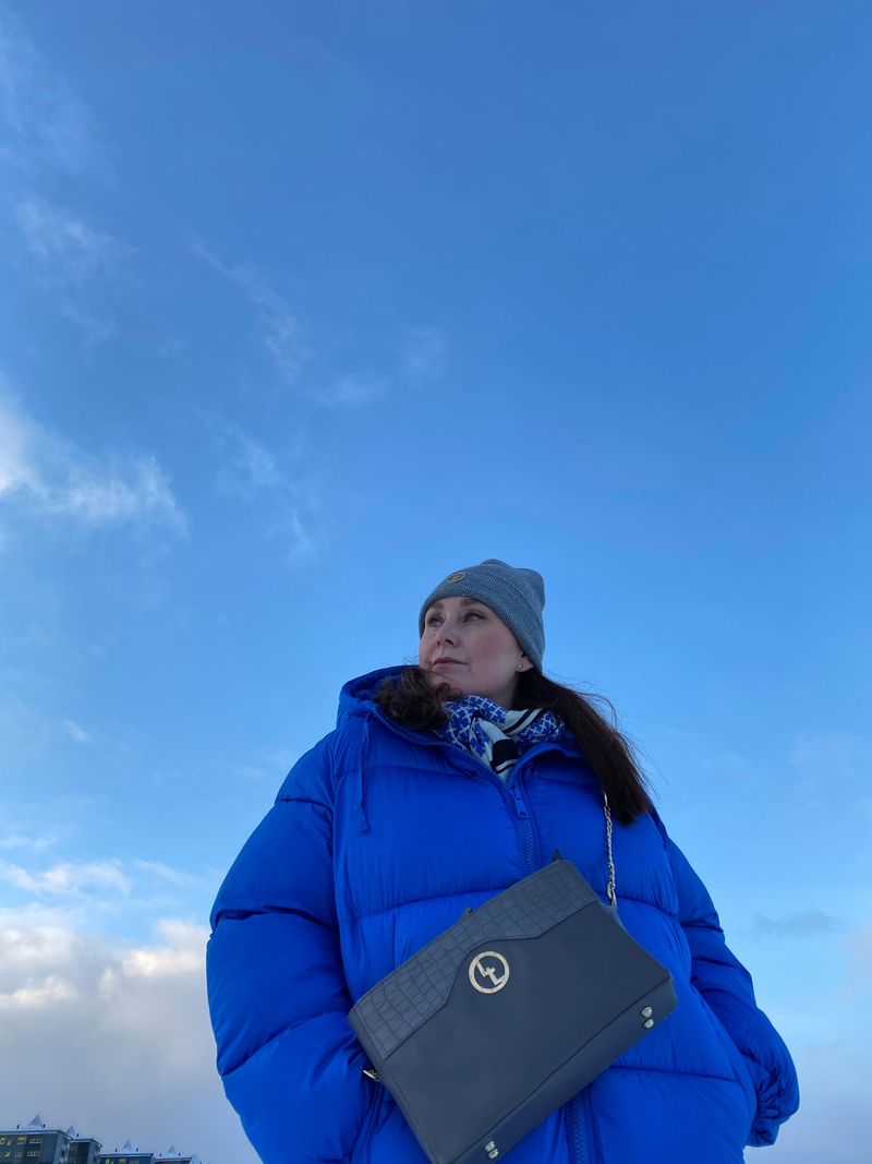 Kvinde iført blå frakke posere mod blå himmel