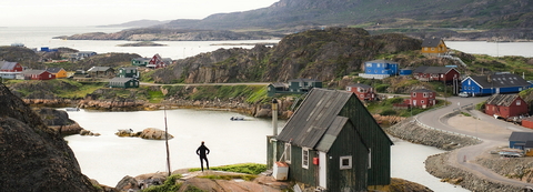 women standing on a cliff near a house looking at the horizon