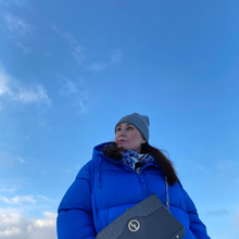 Kvinde iført blå frakke posere mod blå himmel