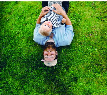 Far og sønn som ligger på gress